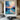 Abstract oil painting of sunset over water with orange and blue color gradients, textured brushstrokes, and dark mountain silhouettes on the horizon.
