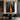 Abstract oil painting of two elongated black silhouettes standing in a vibrant orange light pathway, dark charcoal background enhancing dramatic contrast.