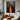 Abstract oil painting of two elongated black silhouettes standing in a vibrant orange light pathway, dark charcoal background enhancing dramatic contrast.