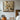 Still life oil painting of daisies in vase with sunlight, coffee and books on table