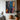 Abstract oil painting with explosive color splashes in white, blue, orange, and pink intersecting on black textured canvas.  