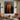 Abstract oil painting of two tall orange silhouettes with mirrored reflections, standing against a deeply textured charcoal-black background.  