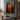 Abstract oil painting of two tall orange silhouettes with mirrored reflections, standing against a deeply textured charcoal-black background.  