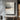Abstract oil painting with layered gray tones, central metallic vein dividing charcoal upper zone and pale gray base, warm umber flecks and drip textures visible.  