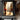 Hand-painted impressionist oil painting of a woman in white sitting on a Paris street with the Eiffel Tower, romantic golden tones and poetic urban scene