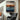 "Strata Hue" abstract artwork featuring horizontal textured bands transitioning in a color gradient from light grey through orange and rust to deep blue and black.
