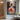 Vertical modern oil painting of woman in pink walking in city at dusk